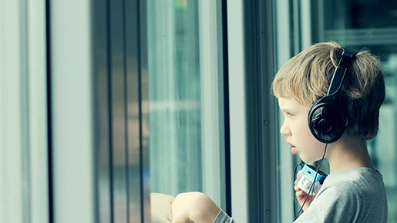 Petit garçon avec des écouteurs qui regarde par la fenêtre