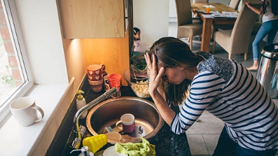 Charge mentale : maman surmenée devant la vaisselle