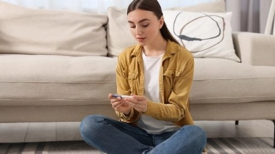 Jeune femme assise sur le sol, tenant un test de grossesse, avec une expression concentrée, dans un salon lumineux.