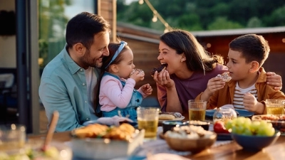 Une famille avec deux enfants réunie autour d’une table pour manger des aliments sains.