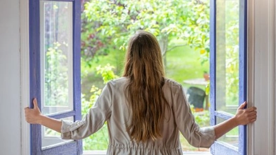 Femme habillée chaudement confortablement assise dans son salon avec un livre.