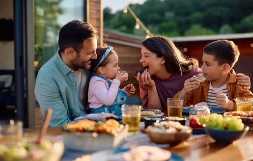 Une famille avec deux enfants réunie autour d’une table pour manger des aliments sains.