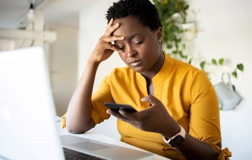 femme devant son ordinateur et son téléphone qui semble fatiguée