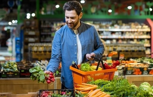 Une jeune femme assise sur un canapé mange un bol de céréales en souriant.