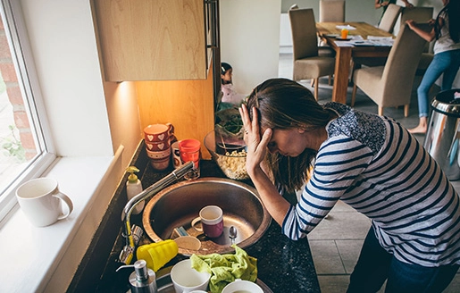 Charge mentale : maman surmenée devant la vaisselle