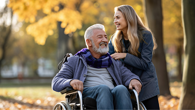 Une jeune femme souriante aidant un vieil homme souriant en chaise roulante