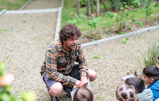 Un jardinier accroupi devant un groupe d’enfants dans un potager.